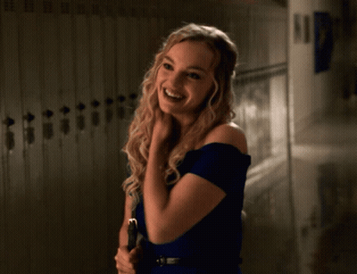 A Woman In A Blue Dress Stands In Front Of Lockers GIF