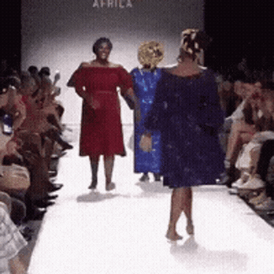 A Woman In A Blue Dress Walks Down A Runway GIF