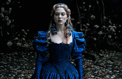 A Woman In A Blue Dress With A Crown On Her Head Sits On The Ground GIF
