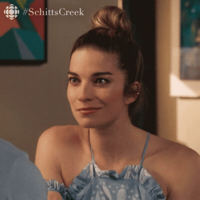 A Woman In A Blue Dress With #Schitts Creek On The Bottom Right GIF