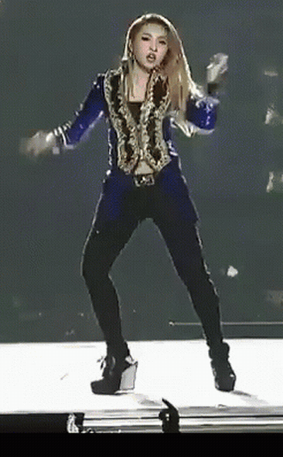 A Woman In A Blue Jacket And Black Pants Is Dancing On Stage GIF