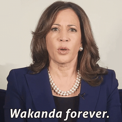 A Woman In A Blue Jacket And Pearl Necklace Says Wakanda Forever GIF