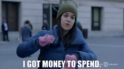 A Woman In A Blue Jacket And Pink Gloves Says I Got Money To Spend GIF
