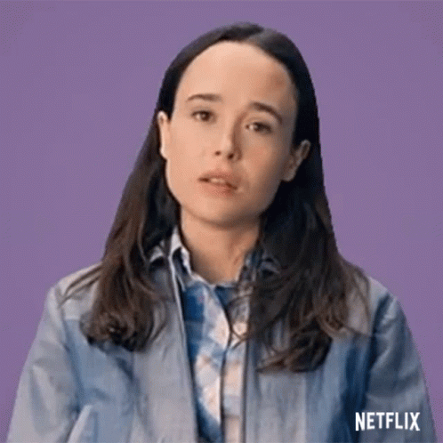 A Woman In A Blue Jacket And Plaid Shirt Is Making A Funny Face . GIF