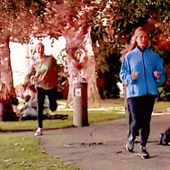 A Woman In A Blue Jacket Is Jogging In The Park GIF
