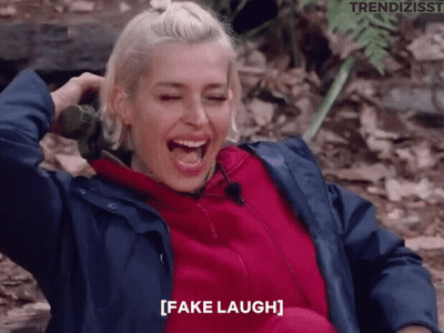 A Woman In A Blue Jacket Is Laughing With The Words Fake Laugh Written Below Her GIF