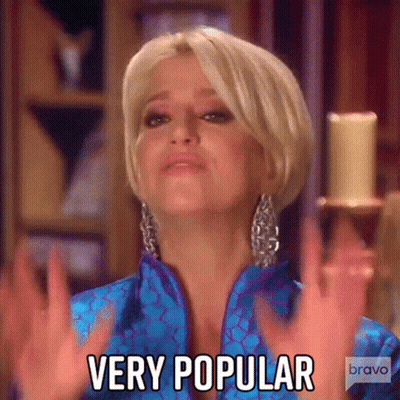 A Woman In A Blue Jacket Is Making A Very Popular Gesture . GIF