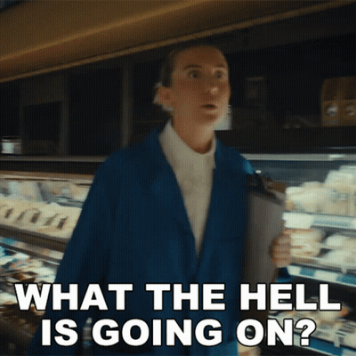 A Woman In A Blue Jacket Is Saying What The Hell Is Going On In A Supermarket GIF
