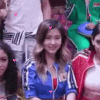 A Woman In A Blue Jacket Is Smiling In A Crowd Of People . GIF