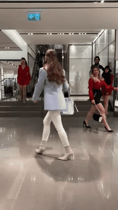 A Woman In A Blue Jacket Is Walking Down Stairs In A Store GIF
