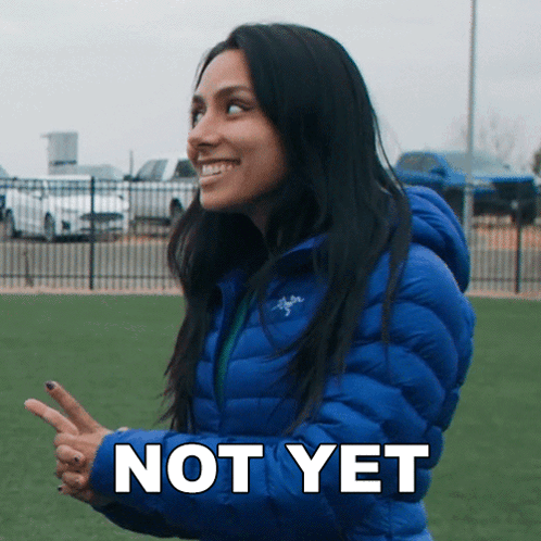 A Woman In A Blue Jacket Says " Not Yet " In White Letters GIF