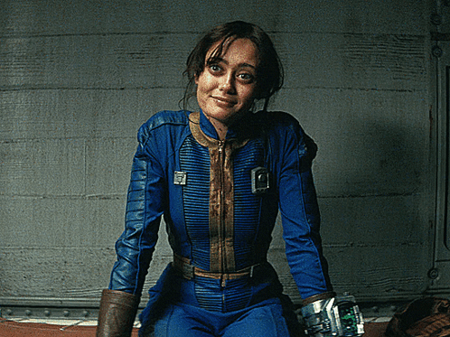 A Woman In A Blue Jumpsuit With A Vault Boy Emblem On The Front GIF
