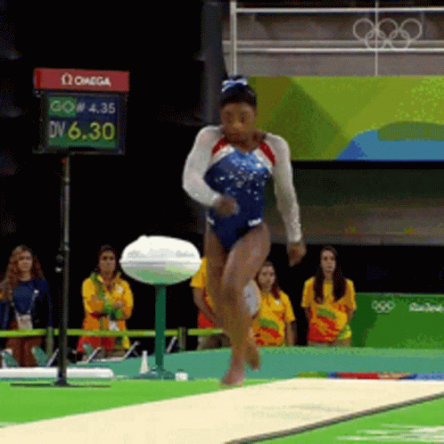 A Woman In A Blue Leotard Is Jumping On A Balance Beam In Front Of A Sign That Says Omega On It GIF