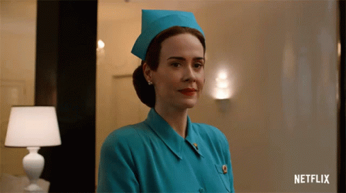 A Woman In A Blue Nurse 'S Uniform With A Netflix Logo Behind Her GIF