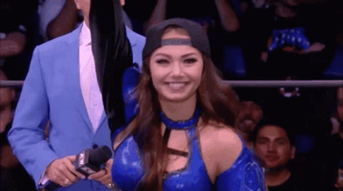 A Woman In A Blue Outfit Is Smiling While Standing Next To A Man In A Blue Suit . GIF