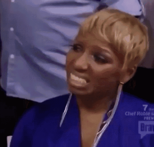 A Woman In A Blue Robe Is Making A Funny Face While Sitting In A Chair . GIF