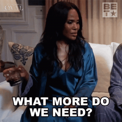 A Woman In A Blue Robe Is Sitting On A Couch Asking What More Do We Need GIF