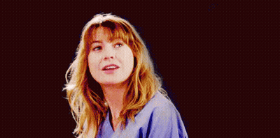 A Woman In A Blue Scrub Is Smiling And Looking At The Camera On A Black Background . GIF