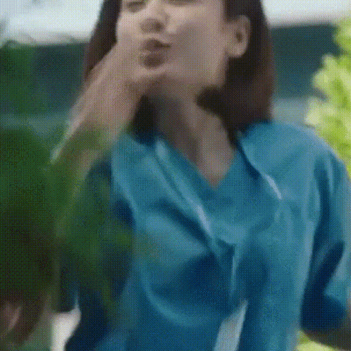 A Woman In A Blue Scrub Top Is Blowing A Kiss GIF