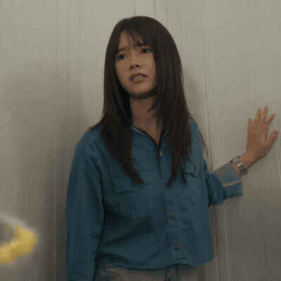 A Woman In A Blue Shirt Has Her Hand On The Wall GIF