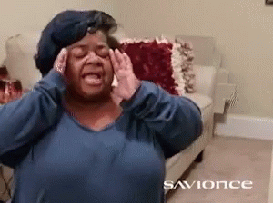 A Woman In A Blue Shirt Is Covering Her Ears With Her Hands In A Living Room With The Words Savonce On The Bottom GIF