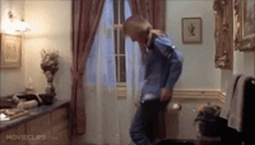 A Woman In A Blue Shirt Is Dancing In A Room With Movie Clips.com On The Bottom Of The Screen . GIF