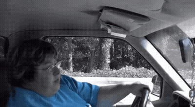A Woman In A Blue Shirt Is Driving A Car With The Number 2 On The Steering Wheel GIF