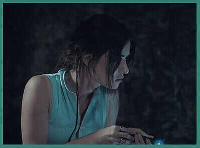 A Woman In A Blue Shirt Is Holding A Flashlight In Her Hand GIF