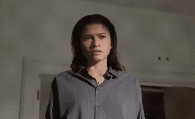 A Woman In A Blue Shirt Is Holding A Knife In Her Hand . GIF