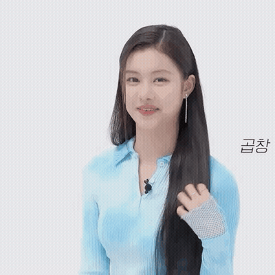 A Woman In A Blue Shirt Is Holding Her Hair And Smiling . GIF