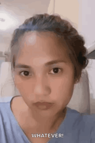 A Woman In A Blue Shirt Is Making A Funny Face And Says `` Whatever '' . GIF