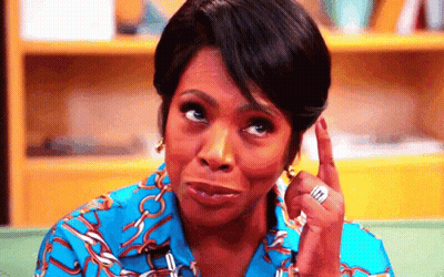 A Woman In A Blue Shirt Is Making A Funny Face While Pointing Up . GIF