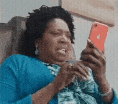 A Woman In A Blue Shirt Is Sitting In A Chair Looking At Her Phone . GIF