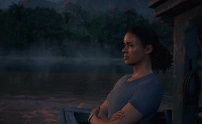 A Woman In A Blue Shirt Is Sitting In Front Of A Lake GIF