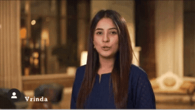 A Woman In A Blue Shirt Is Standing In A Living Room With The Name Vrinda On The Bottom GIF