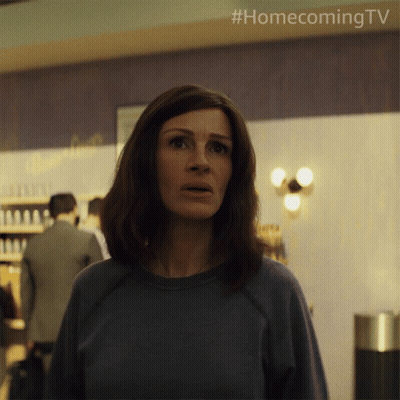A Woman In A Blue Shirt Is Standing In Front Of A Wall That Says Homecoming Tv GIF