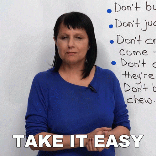 A Woman In A Blue Shirt Is Standing In Front Of A White Board That Says Take It Easy GIF