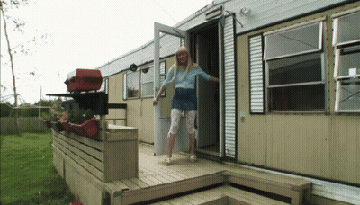 A Woman In A Blue Shirt Is Standing In The Doorway Of A Trailer GIF