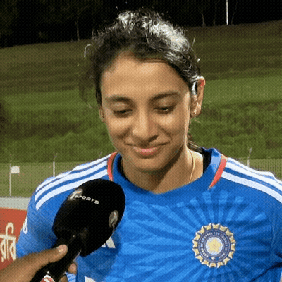 A Woman In A Blue Shirt Is Talking Into A Microphone While Smiling . GIF