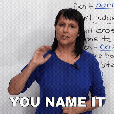 A Woman In A Blue Shirt Stands In Front Of A White Board That Says You Name It GIF