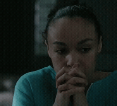 A Woman In A Blue Shirt With Her Hands Folded In Front Of Her Face GIF