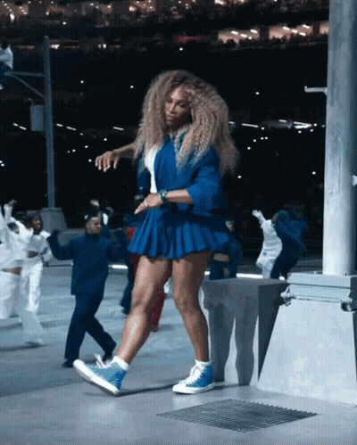A Woman In A Blue Skirt Is Dancing With A Group Of People GIF