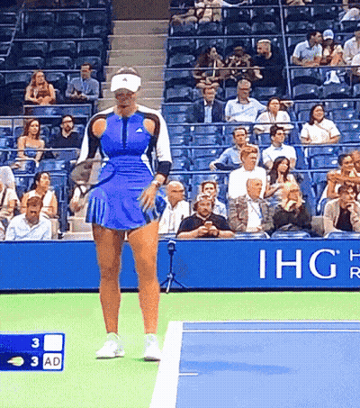 A Woman In A Blue Skirt Is Standing On A Tennis Court In Front Of An Ihg Sign GIF