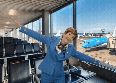 A Woman In A Blue Stewardess Uniform Stands In Front Of A Klm Airplane GIF