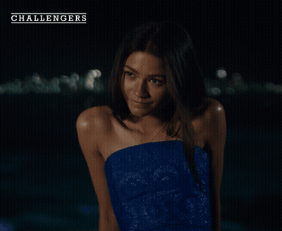 A Woman In A Blue Strapless Dress Is Standing In Front Of A Challenger Logo GIF