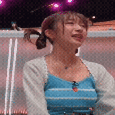 A Woman In A Blue Striped Tank Top Is Crying While Sitting In Front Of A Purple Light . GIF