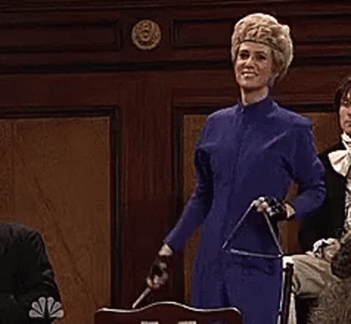 A Woman In A Blue Suit Is Holding A Sword While Standing In Front Of A Group Of People . GIF