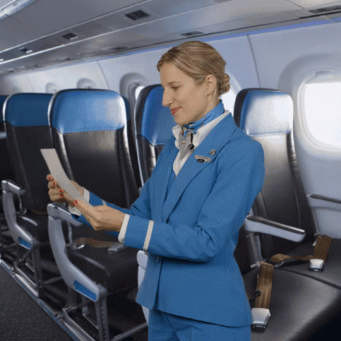 A Woman In A Blue Suit Is Looking At A Piece Of Paper On A Plane GIF
