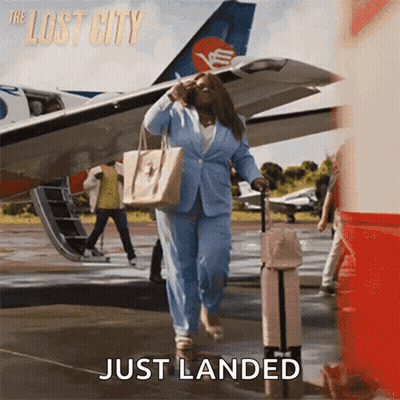 A Woman In A Blue Suit Is Walking Towards An Airplane With The Words Just Landed Below Her GIF