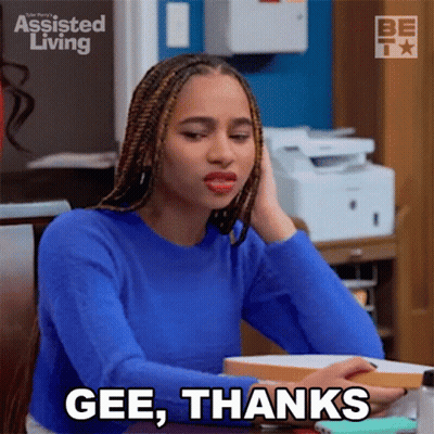 A Woman In A Blue Sweater Is Sitting At A Desk And Saying Gee Thanks GIF